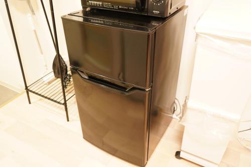 a stainless steel refrigerator with a microwave on top of it at Residence Hotel #2 エアコン付き 無料Wi-Fi in Sapporo