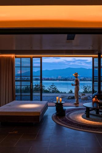 a room with a large window with a view of the water at Lijiang Jijian Xiangwang SOOOAN Luxury Resort Hotel in Lijiang