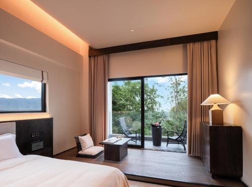 a bedroom with a bed and a large window at Lijiang Jijian Xiangwang SOOOAN Luxury Resort Hotel in Lijiang