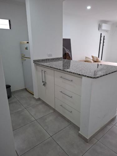 a white kitchen with a counter and a refrigerator at Gramado in Cruz del Eje