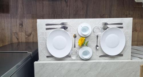 a table with three white plates and a yellow flower at Studio VERONICA in Constanţa