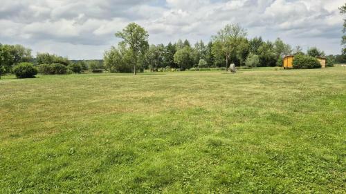 a large grass field with a tent in the distance at La roulotte de l'étang in Chessy-les-Prés
