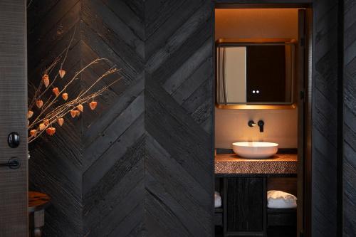 a bathroom with a wooden wall with a sink at Lijiang Jijian Xiangwang SOOOAN Luxury Resort Hotel in Lijiang