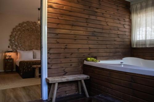 a bathroom with a wooden wall and a bath tub at Beit Oren Hotel in Bet Oren