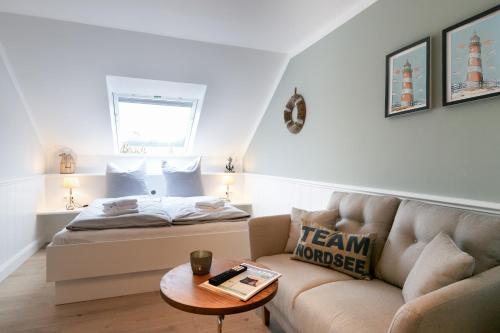 Cette chambre comprend un lit, un canapé et une table. dans l'établissement Top gelegenes Apartment Wattstuuv direkt im Zentrum von St Peter Ording, à Sankt Peter-Ording
