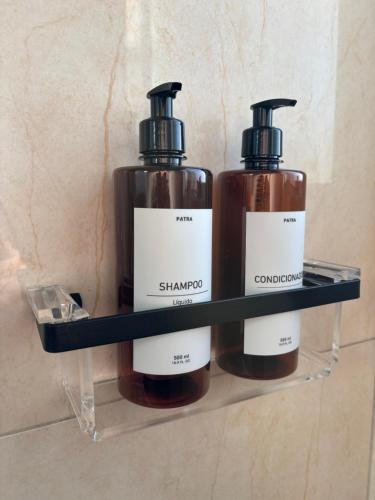 two bottles of shampoo on a shelf in a bathroom at APARTAMENTO no CENTRO in Vacaria