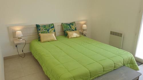 a large green bed in a bedroom with two lamps at Casa di u sole in Santa-Maria-Poggio
