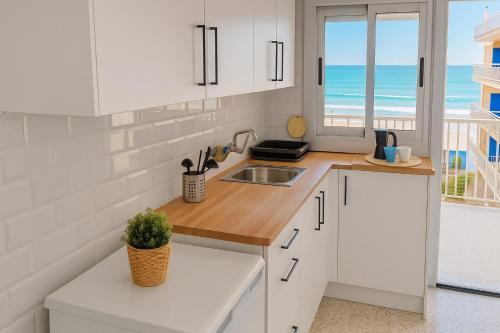 eine Küche mit weißen Schränken und Meerblick in der Unterkunft Apartamento de Toni Playa Bellresguard in Bellreguart