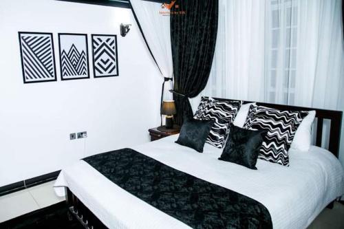 Un dormitorio con una cama con almohadas blancas y negras. en Roots Apart Hotel, en Nairobi