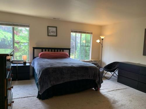 a bedroom with a bed and a desk and windows at Cedar River one bedroom in a four bedroom house in Renton