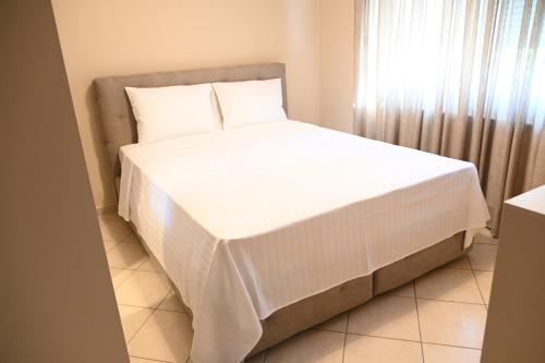 a bed with white sheets and pillows in a room at Garden Bliss 1 Alexandroupolis in Alexandroupoli