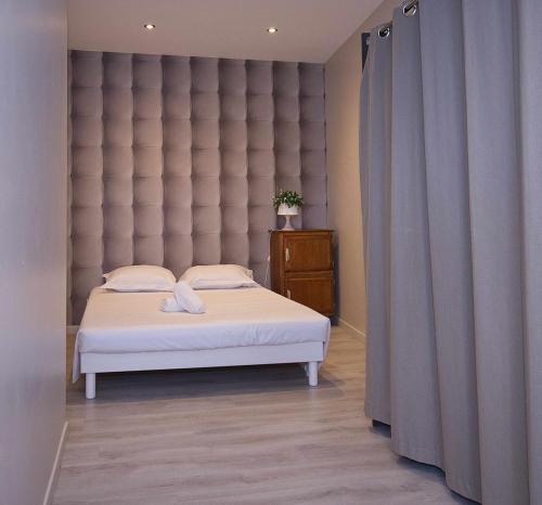 a bedroom with a bed with a large padded headboard at L'octroi de Loches in Loches