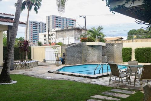 una piscina con tavolo e sedie in un cortile di Beach house in the heart of Atalaia - Casa de praia no coração de Atalaia ad Aracaju