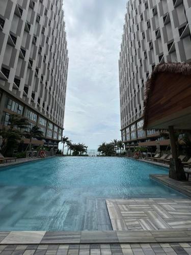 a large swimming pool in the middle of two buildings at Apec Mandala wyndham Apartment - APEC Mui Ne in Mui Ne