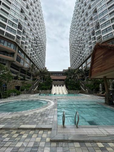 a swimming pool in the middle of two tall buildings at Apec Mandala wyndham Apartment - APEC Mui Ne in Mui Ne