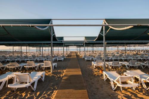 a group of white lounge chairs on the beach at Palm World Side Resort & Spa in Side