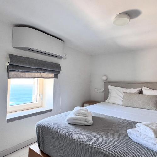 a white bedroom with a bed and a window at Akro Astypalea in Astypalaia
