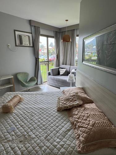 a bedroom with a bed and a living room at Loft Condado Aldeia dos Reis in Mangaratiba