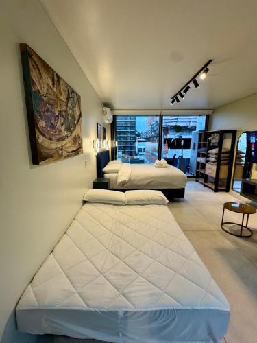 two beds in a bedroom with a large window at Foster Studio - Park in Buenos Aires