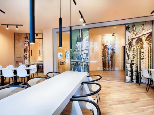 a dining room with white chairs and a table at B&B Hotel Aachen-City in Aachen