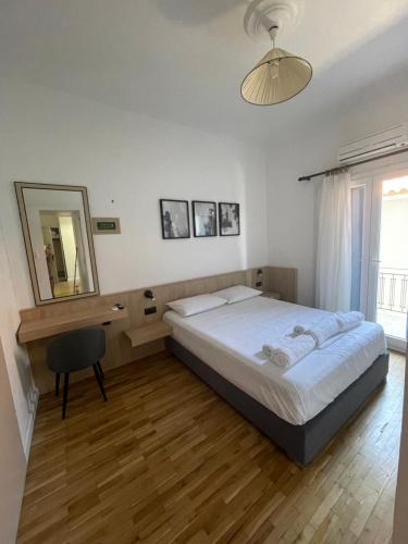 een slaapkamer met een bed, een spiegel en een stoel bij Meraki Inn in Mirina