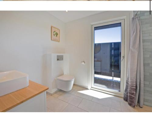 AsperupにあるÆldre charmerende sommerhus i 1 Rækkeのバスルーム(トイレ付)、大きな窓が備わります。