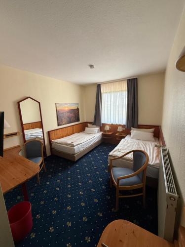 a hotel room with two beds and a table and chairs at Hotel hArz7 in Seesen