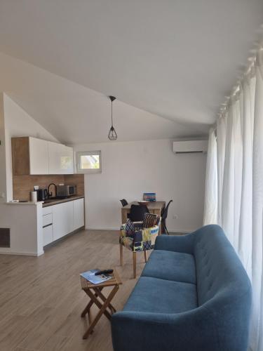 a living room with a blue couch and a kitchen at Seaview Art Studio with balcony in Kaštela