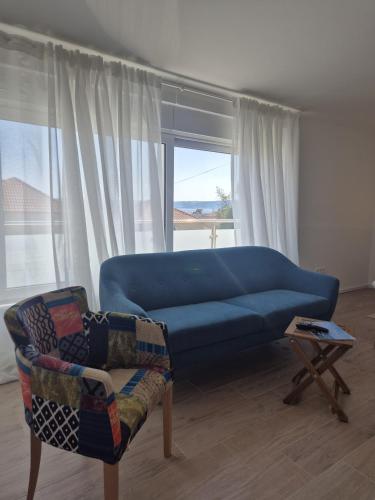 a living room with a blue couch and a chair at Seaview Art Studio with balcony in Kaštela