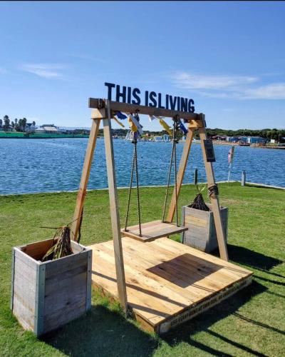 a swing with a sign that reads this is living at Jeffreys Bay - Life on the Canals in Jeffreys Bay
