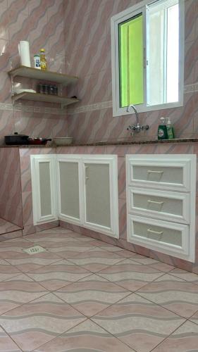 a kitchen with white cabinets and a window at Qantab village apartment in Muscat