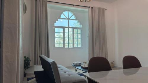 a dining room with a table and chairs and a window at Qantab village apartment in Muscat