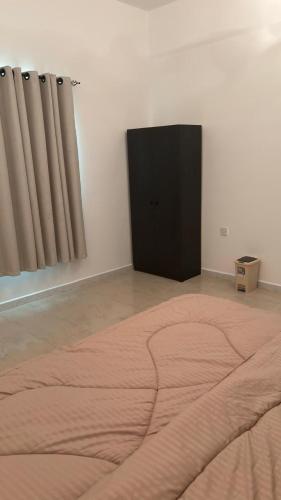 a bedroom with a bed and a black cabinet at Qantab village apartment in Muscat