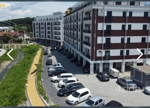 a parking lot with cars parked in front of a building at Apartman Stoiljkovic Vrnjacka Banja in Vrnjci