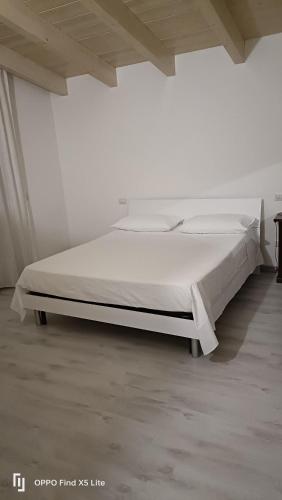 a white bed in a white room with a bed frame at La casa di Erica in Sestu