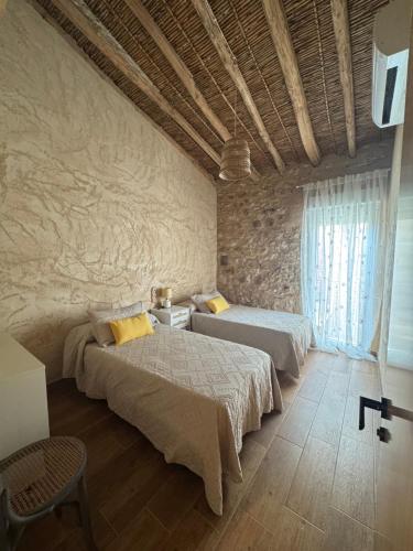 a bedroom with two beds and a stone wall at Ca Salvadora in Beniarrés