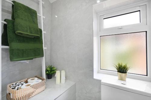 a bathroom with a window and green towels at Denham Close 3 Bedroom and 1 Bathroom Home in Uxbridge