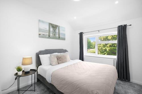 a white bedroom with a bed and a window at Denham Close 3 Bedroom and 1 Bathroom Home in Uxbridge