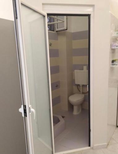 a bathroom with a toilet and a sliding glass door at Vacations in Patra Rooms in Patra