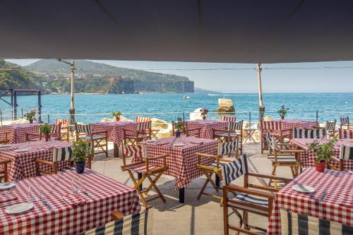 a restaurant with tables and chairs and the ocean at Capo la Gala Hotel&Wellness in Vico Equense