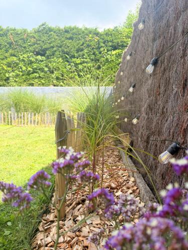 a garden with purple flowers next to a stone wall at La Suite (Ô) Wood & Chic in Cucq
