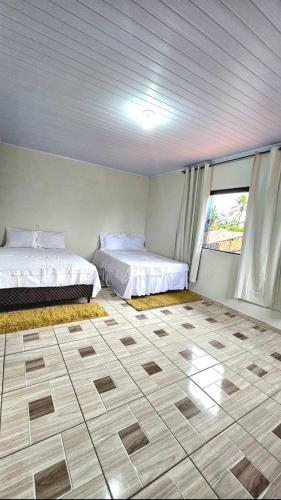 a bedroom with two beds and a large window at Casa Amarela no Centro in Barreirinhas