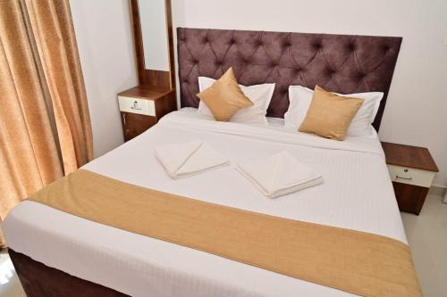 a bedroom with a large bed with white sheets and pillows at Oasis Service Apartments in Mysore