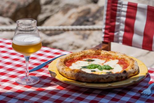 a pizza on a plate next to a glass of beer at Capo la Gala Hotel&Wellness in Vico Equense