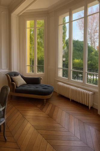 a living room with a couch and two windows at Maison de Maître en Champagne in Vitry-le-François