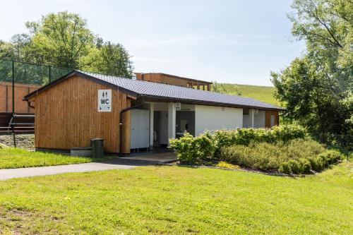 a small building with a sign on the side of it at Teepee a karavanové stání Koupálo Janovičky in Heřmánkovice