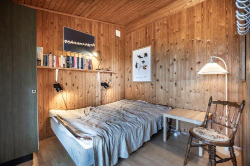 a bedroom with a bed and a chair and a lamp at Large bright summerhouse with sea view and close to the ocean in Lønstrup