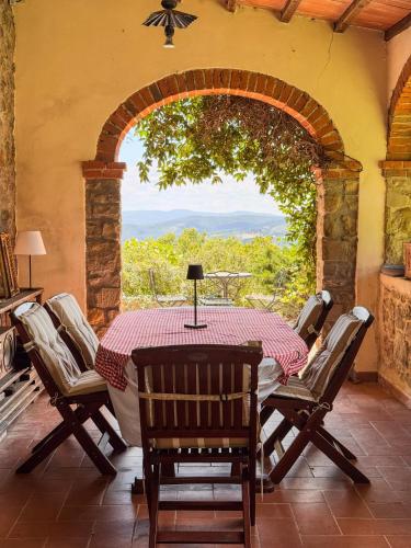 a table and chairs on a patio with an archway at Ferienwohnung Fortuna del Lupo mit Pool und Aussicht in Subbiano