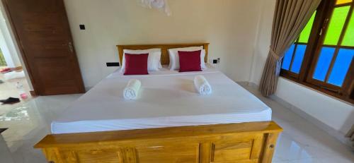 a bedroom with a large white bed with red pillows at Maapagala Resort Sigiriya in Sigiriya