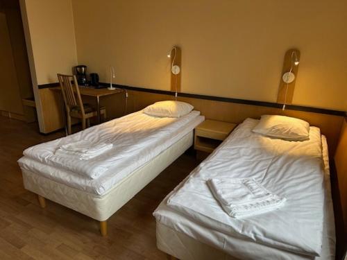 two beds in a room with a table and a chair at Casual Housing Kemi in Kemi